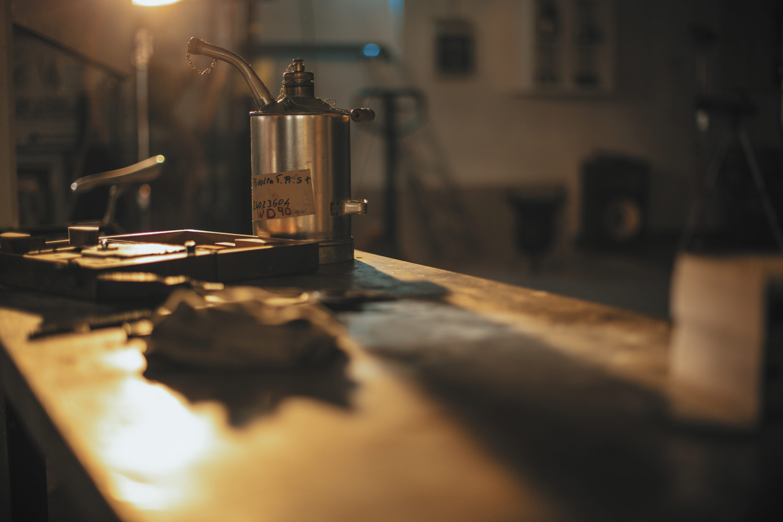 Ölkanne in warm beleuchteter Werkstatt auf Tisch mit Schattenwurf