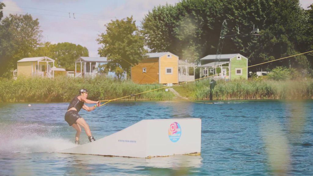 ein Wakeboarder lässt sich auf einem See über eine Rampe ziehen